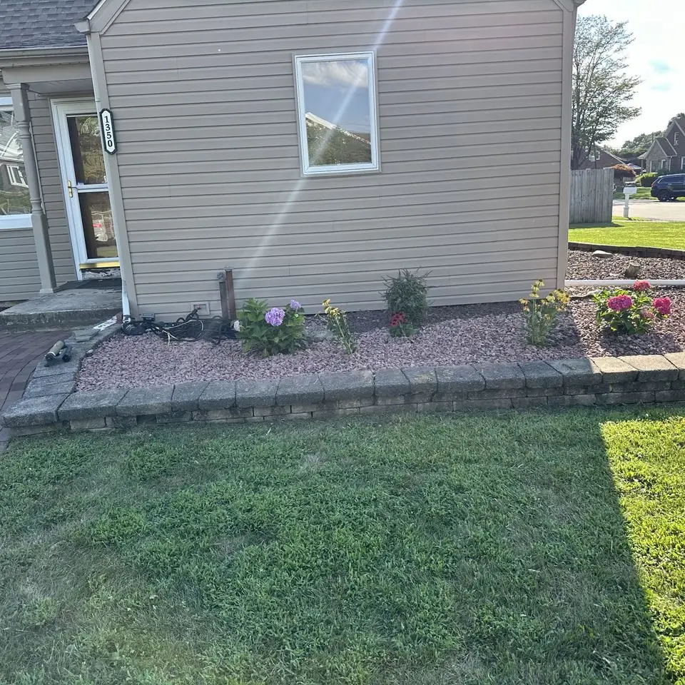 Brick-edged flower bed with fresh mulch along the side of a house