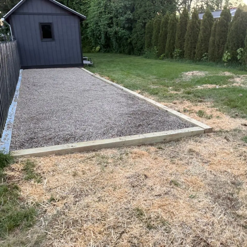 Gravel pad installed beside a backyard shed