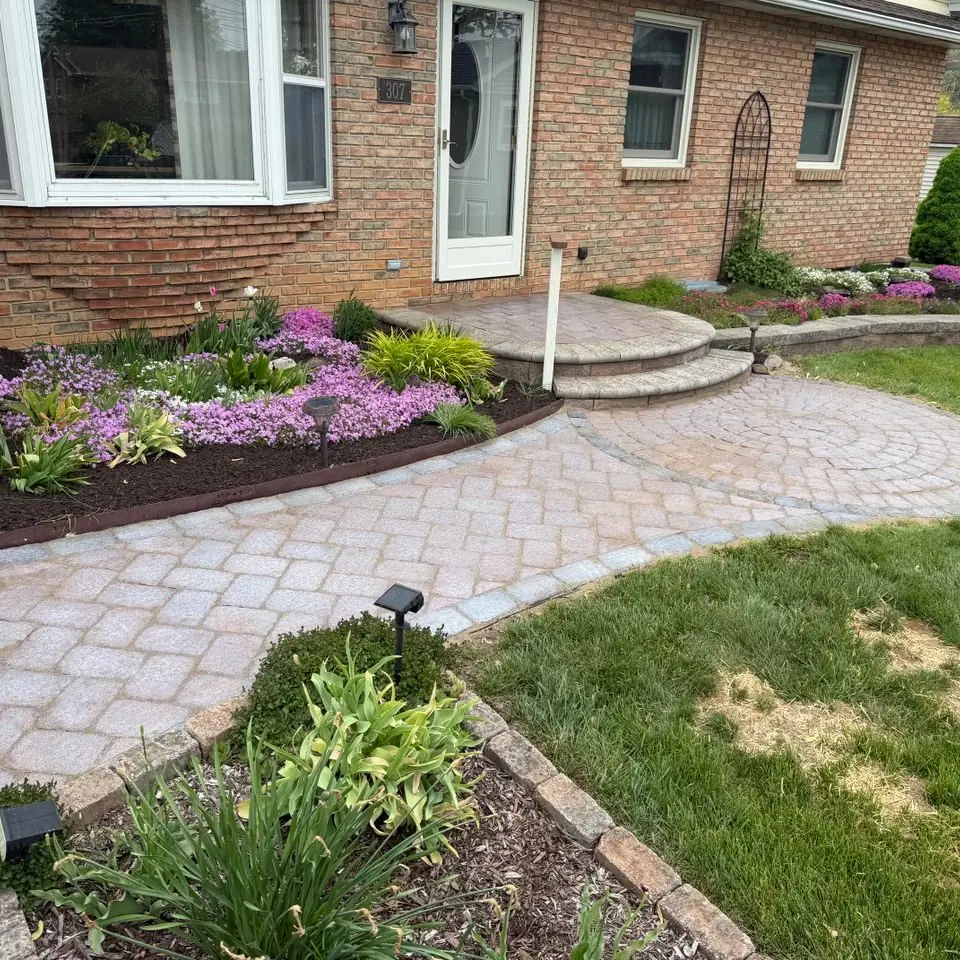 Paver walkway and flower beds in front of a brick home